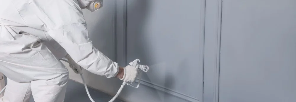 Person in Schutzkleidung sprüht Wand